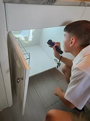 Checking under the sink to ensure there are no plumbing issues.